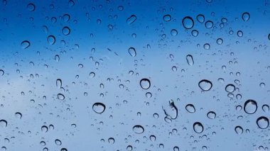 Su damlacıkları cam yüzey üzerinden mavi gökyüzüne karşı perspektif ile multimedya içeriği için iyidir