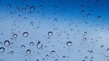 Su damlacıkları cam yüzey üzerinden mavi gökyüzüne karşı perspektif ile multimedya içeriği için iyidir