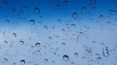 Su damlacıkları cam yüzey üzerinden mavi gökyüzüne karşı perspektif ile multimedya içeriği için iyidir