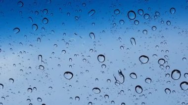 Su damlacıkları cam yüzey üzerinden mavi gökyüzüne karşı perspektif ile multimedya içeriği için iyidir