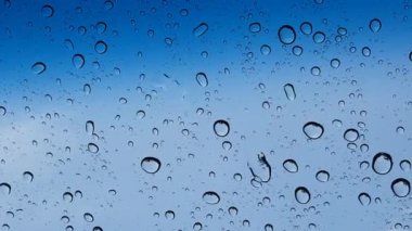 Su damlacıkları cam yüzey üzerinden mavi gökyüzüne karşı perspektif ile multimedya içeriği için iyidir