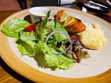 Kızarmış somon balığı, salata ve patates püresi ile servis edilir. Üstüne limon, mükemmel bir yemek tabağında servis edilir.