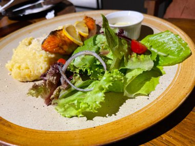 Kızarmış somon balığı, salata ve patates püresi ile servis edilir. Üstüne limon, mükemmel bir yemek tabağında servis edilir.