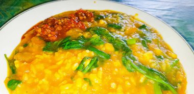 tinutuan, bubur manado, indonesian traditional porridge dish mixed of rice, pumpkin, and kangkung vegetable served with salty fish and sambal