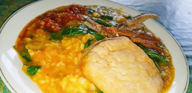 tinutuan, bubur manado, indonesian traditional porridge dish mixed of rice, pumpkin, and kangkung vegetable served with salty fish and sambal