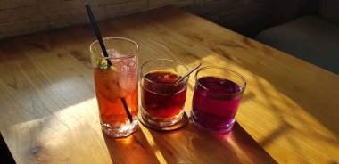 Şeffaf bardaklar, içinde tatlı içecekler, renkli içecekler, gölgeli masa arkası, bir bar restoranında buz küpleri.