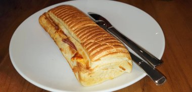 Meşhur bir restoranda ızgara biftek mantarlı Panini veya ahşap masada beyaz tabakla servis edilen sandviç.