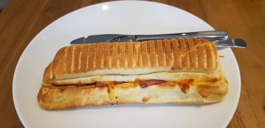 Meşhur bir restoranda ızgara biftek mantarlı Panini veya ahşap masada beyaz tabakla servis edilen sandviç.