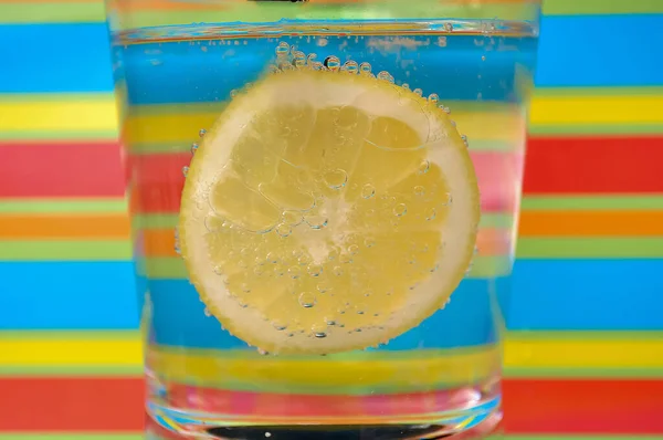Lemonade fizzy drink in a clear glass with colorful background showing fizzy bubbles good for your multimedia content creation background