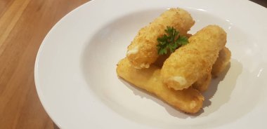 Ana menüden önce bir restoranda aperatif ya da atıştırmalık olarak servis edilen beyaz tabağa konmuş kızarmış mozzarella peyniri çubukları.