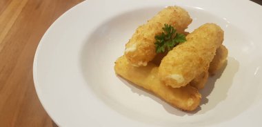 Ana menüden önce bir restoranda aperatif ya da atıştırmalık olarak servis edilen beyaz tabağa konmuş kızarmış mozzarella peyniri çubukları.