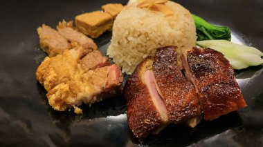 Süper lezzetli kızarmış pekin ördeği Hainan pilavı ve kızarmış domuz göbeği ile servis edilir. Prestijli doğu yemeği restoranında lezzetli Çin yemeği.