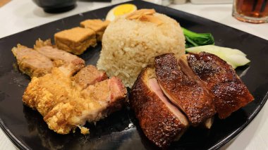 Süper lezzetli kızarmış pekin ördeği Hainan pilavı ve kızarmış domuz göbeği ile servis edilir. Prestijli doğu yemeği restoranında lezzetli Çin yemeği.