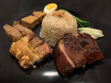 Süper lezzetli kızarmış pekin ördeği Hainan pilavı ve kızarmış domuz göbeği ile servis edilir. Prestijli doğu yemeği restoranında lezzetli Çin yemeği.
