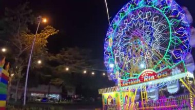 Geceleyin Funfair dönme dolabını aydınlatır, gece vakti lunaparkta dönme dolabı hareket ettirirdi.