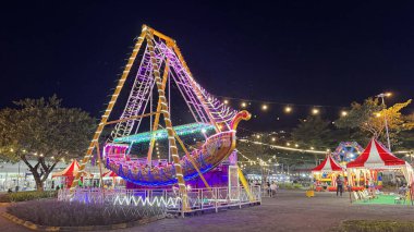 Aydınlatılmış korsan gemisi Endonezya 'daki Noel pazarında eğlence parkında salıncak gezisi yapıyor.