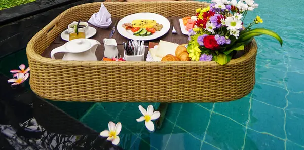 Set of floating breakfast tray in swimming pool. Breakfast in swimming pool, floating breakfast set in tray in resort in Bali