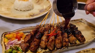 Baharat ve tatlı soya sosuyla marine edilmiş ev yapımı sığır eti, kişniş bifteği satay, soğan, biber, soya sosu ve domates ile servis edilen tabakta. Endonezya geleneksel yemek seti maranggi