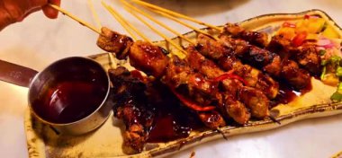 Baharat ve tatlı soya sosuyla marine edilmiş ev yapımı sığır eti, kişniş bifteği satay, soğan, biber, soya sosu ve domates ile servis edilen tabakta. Endonezya geleneksel yemek seti maranggi
