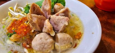 Bakso, indonesian meatball style served with beef broth soup and noodle springkled with fried onion and spring onion coupled with chili sauce on the top, very famous Asian street food clipart