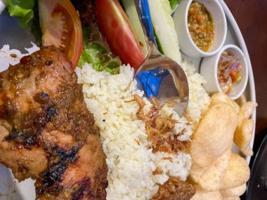 Nasi uduk ayam bakar, ya da hindistan cevizi sütü aromalı pirinç ızgara tavuk, taze salata ve biber ezmesi geleneksel Endonezya yemeği, Endonezya sokak yemeği, ev yapımı yemek