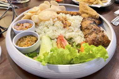 Nasi uduk ayam bakar, ya da hindistan cevizi sütü aromalı pirinç ızgara tavuk, taze salata ve biber ezmesi geleneksel Endonezya yemeği, Endonezya sokak yemeği, ev yapımı yemek