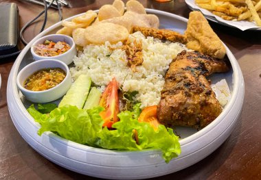 Nasi uduk ayam bakar, ya da hindistan cevizi sütü aromalı pirinç ızgara tavuk, taze salata ve biber ezmesi geleneksel Endonezya yemeği, Endonezya sokak yemeği, ev yapımı yemek