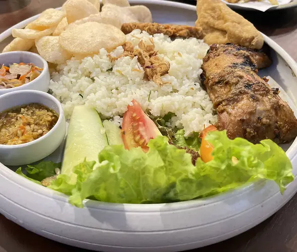 stock image Nasi uduk ayam bakar, or coconut milk flavor rice served with grilled chicken, fresh salad, and chili paste traditional Indonesian food, indonesian street food, homemade food