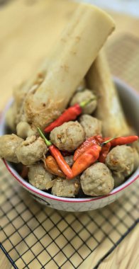 Delicious Indonesian meatballs with huge bones contains bone marrow in spicy beef broth and chilies served in a bowl clipart