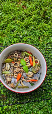 Endonezya ev yemeği menüsü, siyah mürekkep soslu sotelenmiş mürekkep balığı baharatlı Tumis Cumi Hitam, içinde acı biber, zencefil ve limon yaprağı bulunan bir kâse.