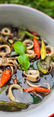 Endonezya ev yemeği menüsü, siyah mürekkep soslu sotelenmiş mürekkep balığı baharatlı Tumis Cumi Hitam, içinde acı biber, zencefil ve limon yaprağı bulunan bir kâse.