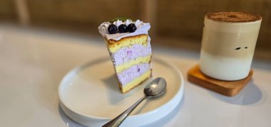 Beyaz tabakta taze böğürtlenlerle süslenmiş bir dilim yaban mersinli kek, lezzetli katmanlı pasta, kafenin üst manzarası.