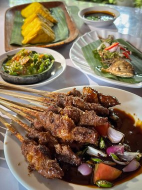 Kuzu eti, ızgara şiş. Soya soslu, soğanlı, domatesli, salatalıklı ve kırmızı biberli, beyaz tabakta servis edilmiş.