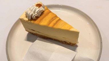 Limonlu cheesecake taze pişmiş dilim, New York usulü klasik peynirli kek tatlı tabağında. Tatlı kaşığıyla servis edilen beyaz tabakta bir dilim lezzetli pasta, yemek kitabına iyi gelir.