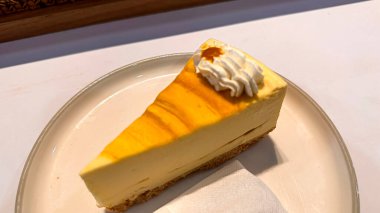 Limonlu cheesecake taze pişmiş dilim, New York usulü klasik peynirli kek tatlı tabağında. Tatlı kaşığıyla servis edilen beyaz tabakta bir dilim lezzetli pasta, yemek kitabına iyi gelir.
