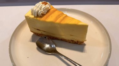 Limonlu cheesecake taze pişmiş dilim, New York usulü klasik peynirli kek tatlı tabağında. Tatlı kaşığıyla servis edilen beyaz tabakta bir dilim lezzetli pasta, yemek kitabına iyi gelir.