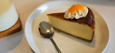 Limonlu cheesecake taze pişmiş dilim, New York usulü klasik peynirli kek tatlı tabağında. Tatlı kaşığıyla servis edilen beyaz tabakta bir dilim lezzetli pasta, yemek kitabına iyi gelir.