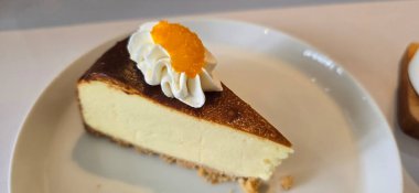 Limonlu cheesecake taze pişmiş dilim, New York usulü klasik peynirli kek tatlı tabağında. Tatlı kaşığıyla servis edilen beyaz tabakta bir dilim lezzetli pasta, yemek kitabına iyi gelir.