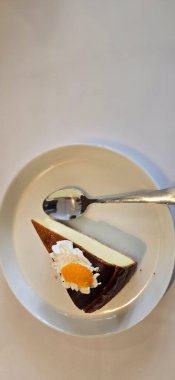 Limonlu cheesecake taze pişmiş dilim, New York usulü klasik peynirli kek tatlı tabağında. Tatlı kaşığıyla servis edilen beyaz tabakta bir dilim lezzetli pasta, yemek kitabına iyi gelir.