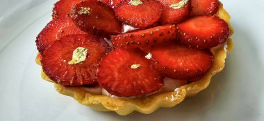 Lezzetli çilekli tart ya da çilekli tart ve yenilebilir altın taneleriyle süslenmiş krema. Multimedya tarifi içeriği yaratmak için iyi.