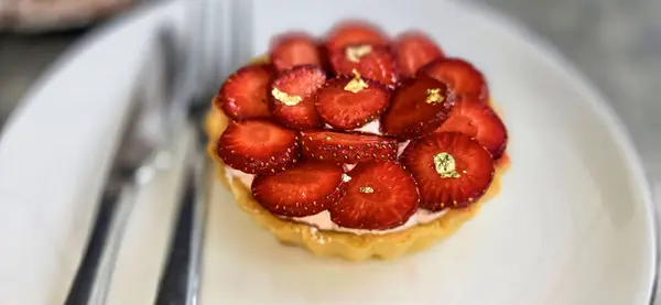 stock image Delicious strawberry tart or tartlet with cut out strawberries and whipped cream decorated with edible gold flakes, good for multimedia recipe content creation