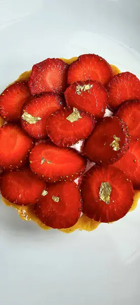 stock image Delicious strawberry tart or tartlet with cut out strawberries and whipped cream decorated with edible gold flakes, good for multimedia recipe content creation