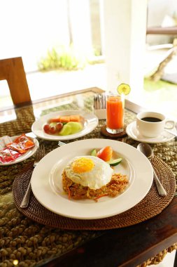 Asyalı stili bir otelde havuzun yanında kahvaltı. Güneşli yaz günlerinde tatil köyündeki güzel mavi havuz kenarında nefis yiyeceklerle dolu bir masa. Dinlenme ve tatil lüks otel, tatil