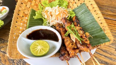 Chicken grilled satay skewers served with lime and peanut sauce on black, top view. Asian thai style food, good for cooking book idea, content creation clipart