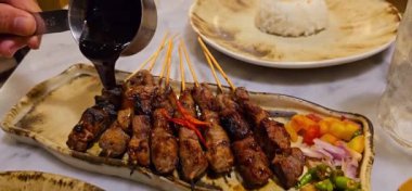 Baharat ve tatlı soya sosuyla marine edilmiş ev yapımı sığır eti, kişniş bifteği satay, soğan, biber, soya sosu ve domates ile servis edilen tabakta. Endonezya geleneksel yemekleri