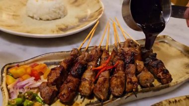 Baharat ve tatlı soya sosuyla marine edilmiş ev yapımı sığır eti, kişniş bifteği satay, soğan, biber, soya sosu ve domates ile servis edilen tabakta. Endonezya geleneksel yemekleri