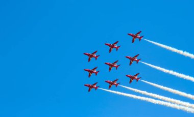 Kırmızı oklar İngiltere 'de mavi gökyüzünde manevra yapıyor. Uçak jeti Cosford United Kindom' daki bir hava gösterisinde akrobatik ve uçan formasyonlar yapıyor.