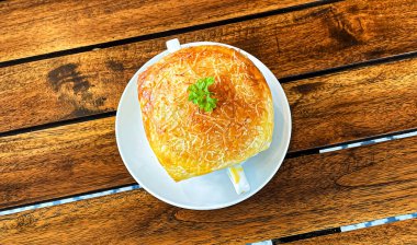 Lahana, kabak, fasulye, patates, kereviz, havuç, soğan, domates hamuru, ekstra bakire zeytinyağı, acı biber ve tavuk veya pastırmadan yapılmış ahşap masanın üstünde altın sarısı çıtır çıtır tavuk çorbası veya ev yapımı zuppa çorbası..