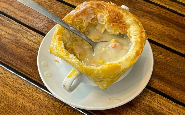 Lahana, kabak, fasulye, patates, kereviz, havuç, soğan, domates hamuru, ekstra bakire zeytinyağı, acı biber ve tavuk veya pastırmadan yapılmış ahşap masanın üstünde altın sarısı çıtır çıtır tavuk çorbası veya ev yapımı zuppa çorbası..