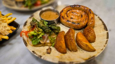 Ağız sulandıran Almanların en kötü kıvrımlı sosisi ızgara sosis, patates kızartması ve köy tabağında servis edilen taze sebzeler. Akşam yemeği aşıkları için mükemmel. Yürekli ve lezzetli yemekleri takdir ederler..